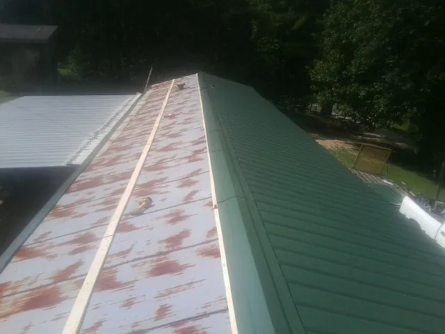 Old rusted panels beside newly installed green metal roofing — Wind Damage Roof Repair by Roofing Brothers in Moore