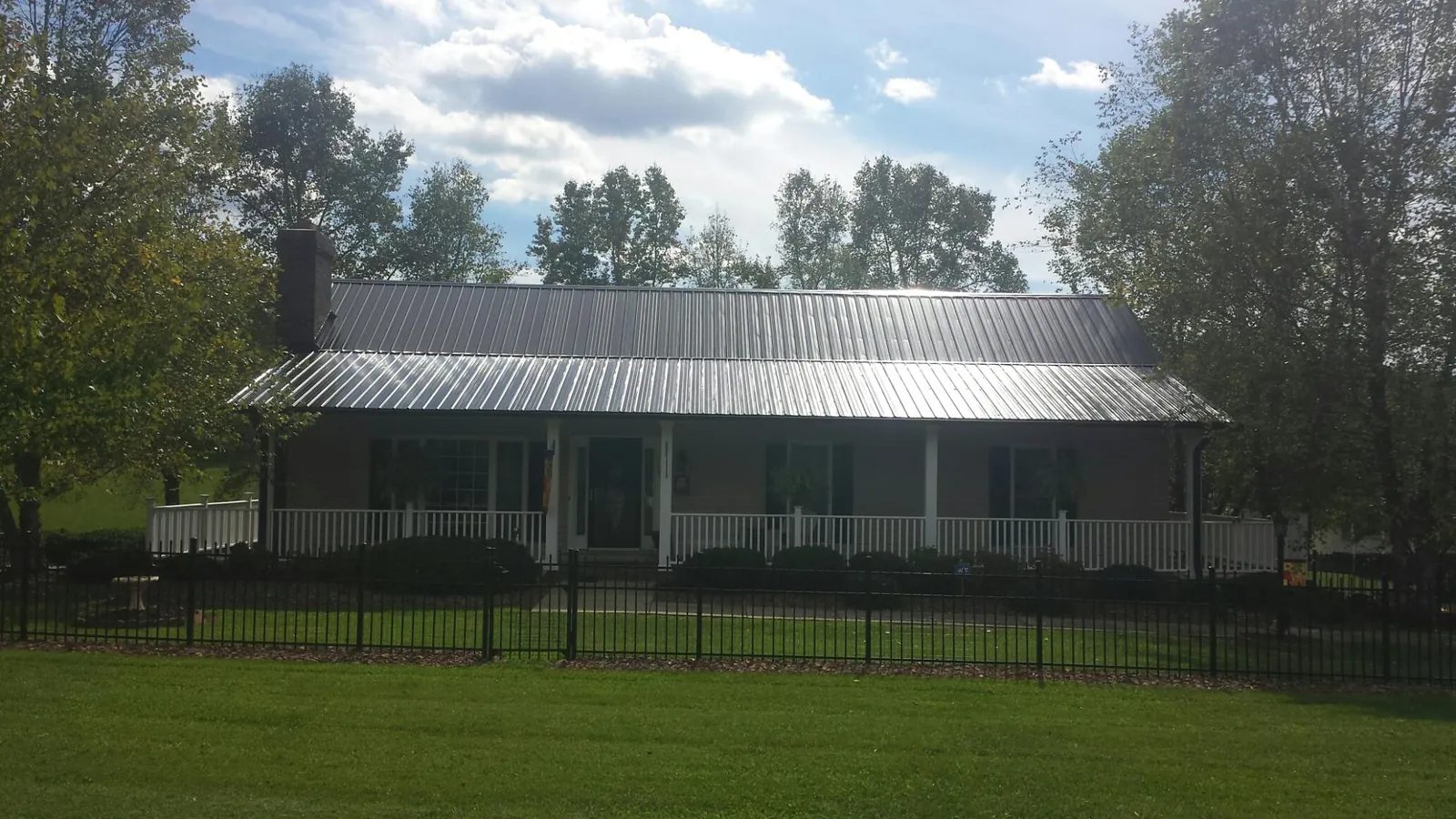 Gray metal roof on a brick ranch with a full width front porch — Gutter Guard Installation work by our crew in Moore